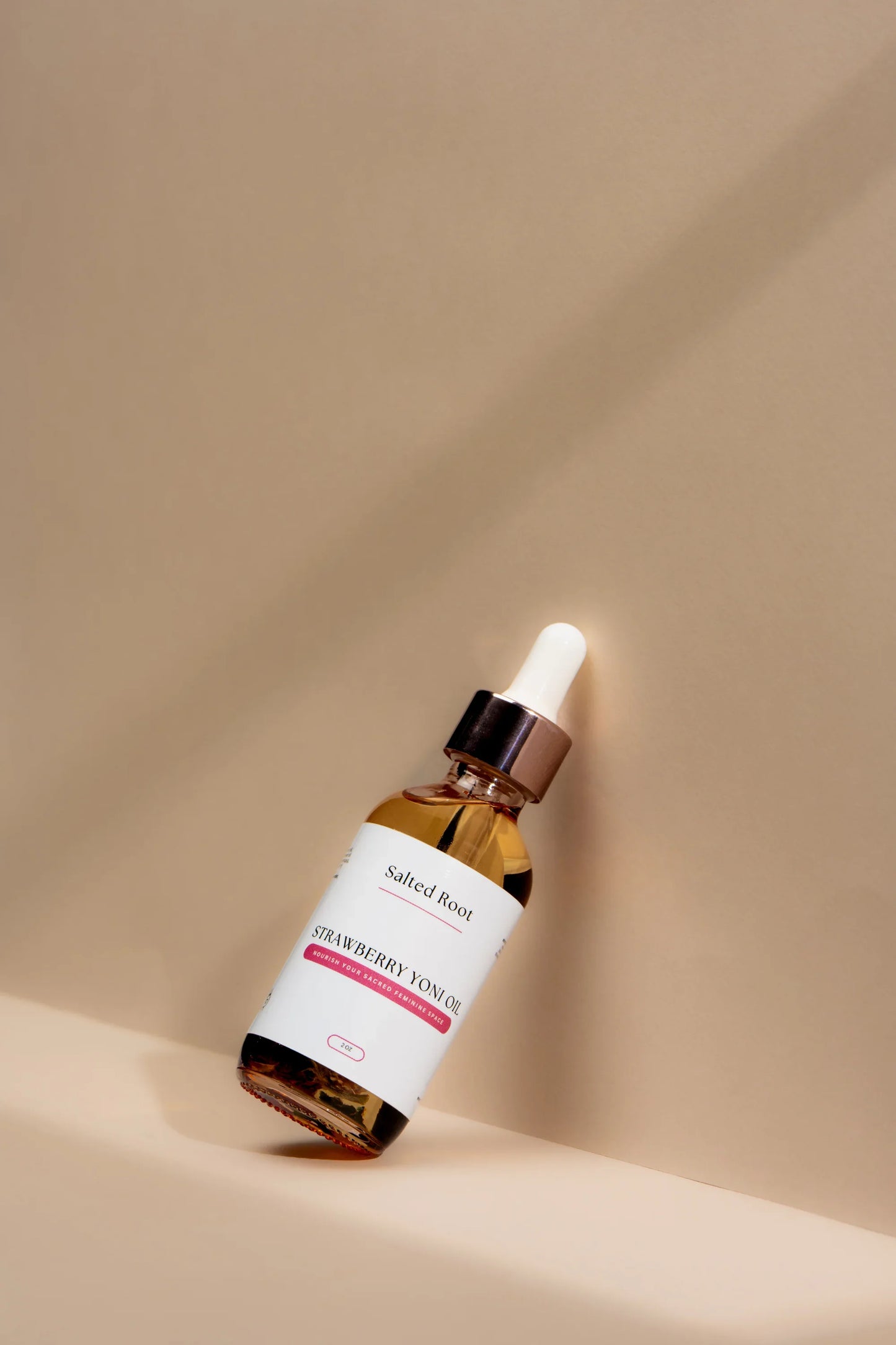 Strawberry Yoni Oil with dropper on a beige background